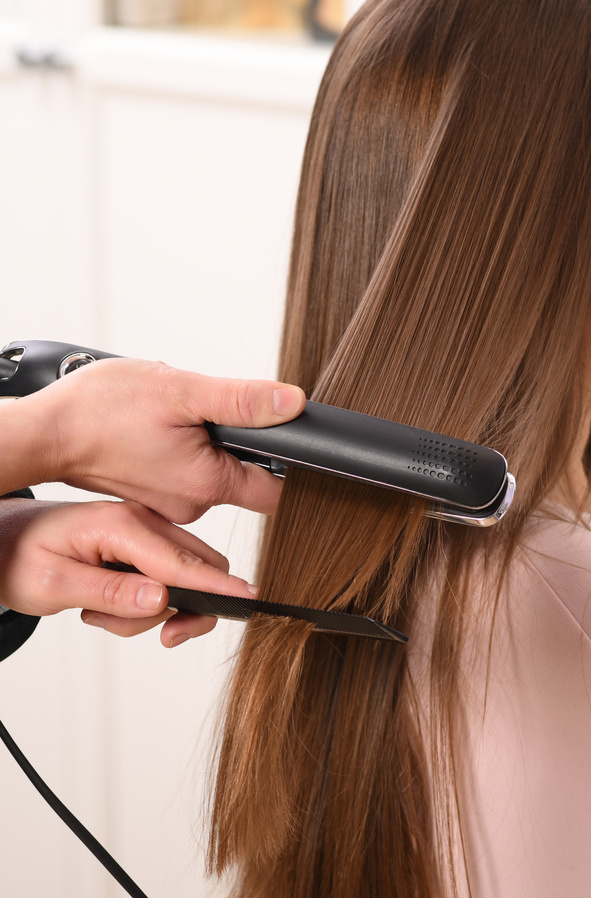 Person Using Hair Straightener on a Client