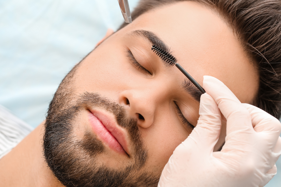 Young Man Undergoing Eyebrow Correction Procedure in Beauty Salon